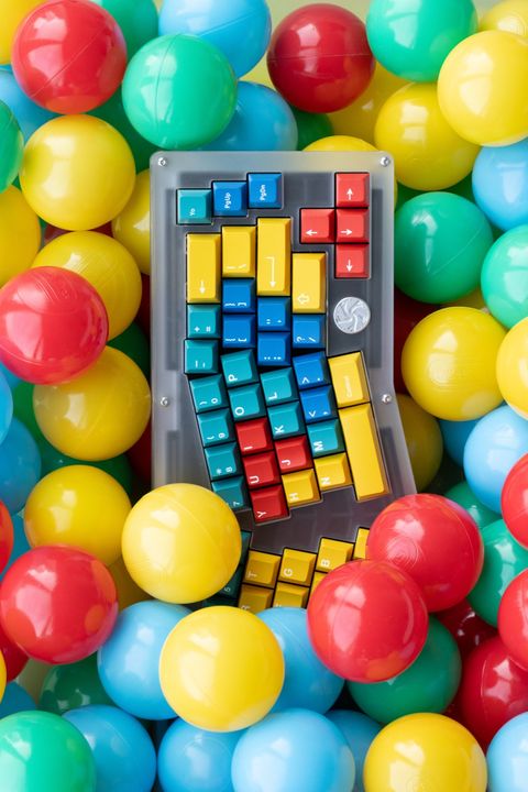 Neon yellow mechanical keyboard floating among tennis balls against a green background