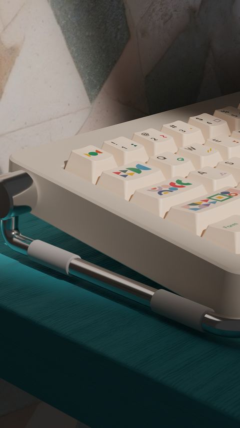 A cream keyboard on a teal shelf, cut by a bold diagonal band of light across a patterned wall