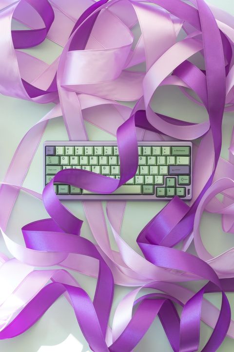 Pastel green mechanical keyboard tangled in pink and purple ribbon