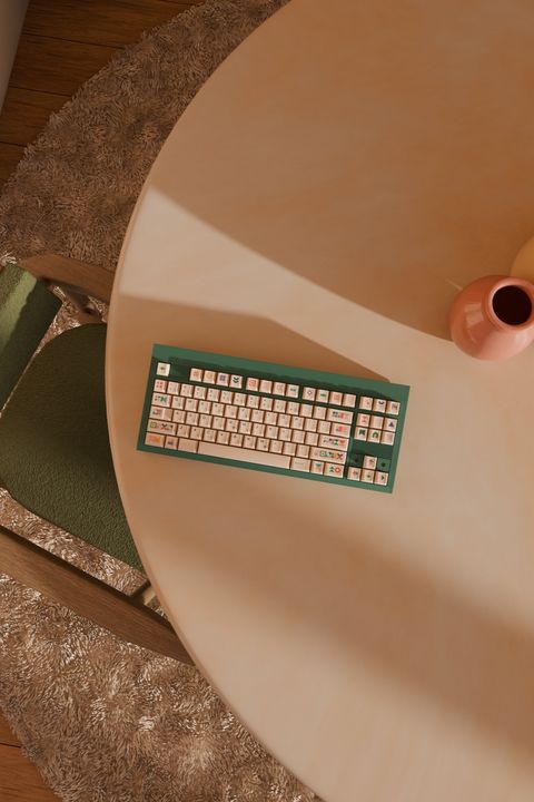 Overhead 3D render of a green keyboard on a round table beside a shag rug and wood flooring