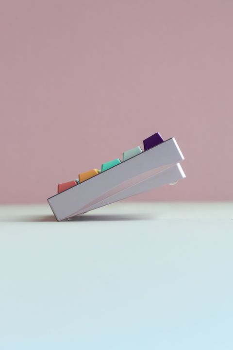 Colorful abstract keycap array photographed at an angle against a pink background