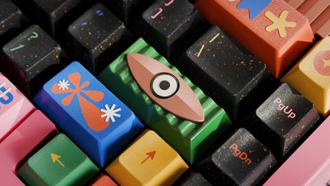 A pink keyboard fitted with the GMK CYL Motif set, the Enter artisan in its place among cream, black and colourful keys