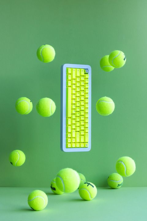 Gray mechanical keyboard with colorful keycaps nestled in a ball pit of red, yellow, teal, and blue balls