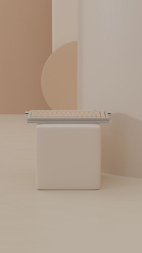 A small keyboard on a white cube in a soft pastel set of arches and blocks