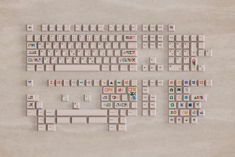A render of the full kit laid out on travertine: rows of cream caps with colourful geometric sub-legends and shape novelties