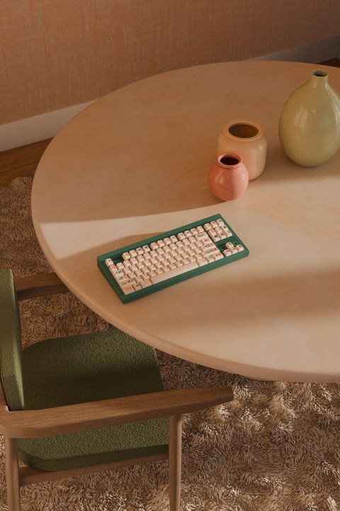 Looking down on the keyboard on a round table with a green chair, small vases and a soft rug