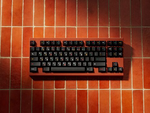 3D render of the GMK Tribal keyboard on a warm terracotta tile backdrop