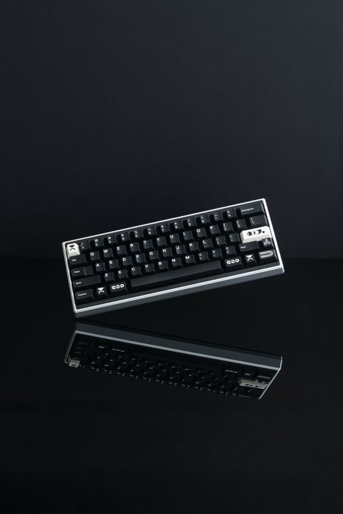 Black and silver mechanical keyboard tilted on a glossy black reflective surface