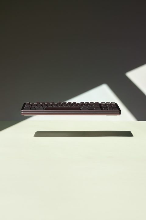 Dark maroon mechanical keyboard floating in shadow with a dramatic diagonal beam of light