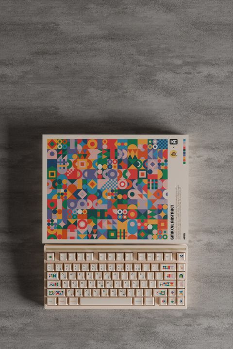 Top-down view of the open box art and the keyboard side by side on grey concrete