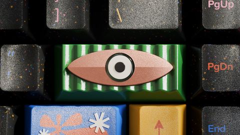 Close-up of the artisan's eye among speckled black keys and a blue keycap with a coral flower legend